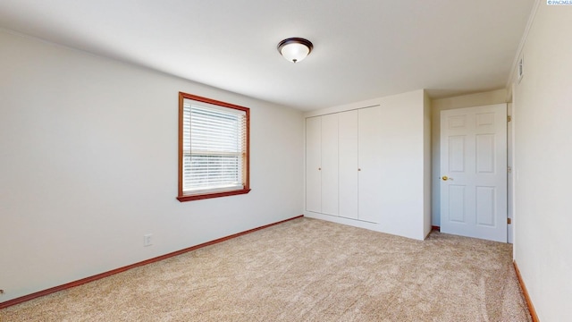 unfurnished bedroom with light carpet, a closet, and baseboards