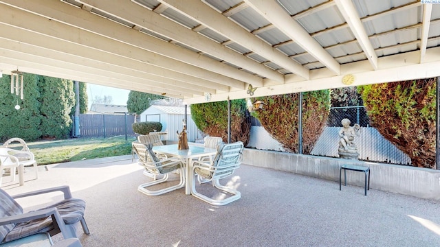 view of patio / terrace with a storage unit, fence, an outdoor structure, and outdoor dining space