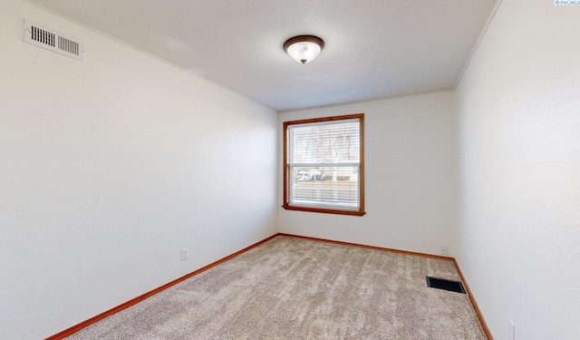 spare room featuring light carpet, visible vents, and baseboards