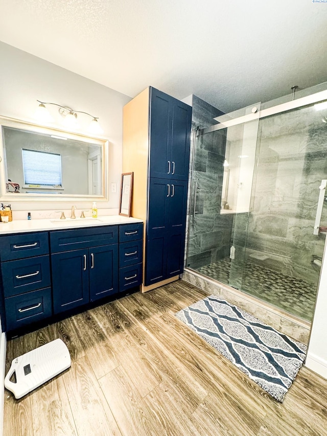 bathroom with vanity, wood-type flooring, a textured ceiling, and walk in shower