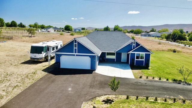 view of front facade featuring a garage, a mountain view, and a front lawn