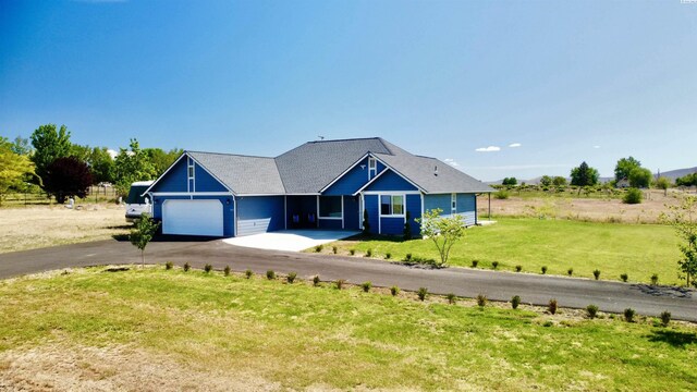 view of front of property with a garage, a front lawn, and a rural view