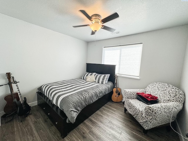 bedroom with ceiling fan, a textured ceiling, and dark hardwood / wood-style flooring