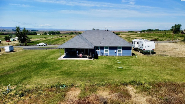 back of house with a yard and a rural view