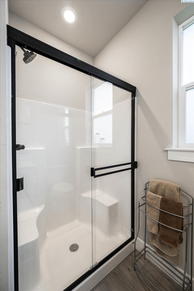 bathroom with hardwood / wood-style flooring and a shower with shower door