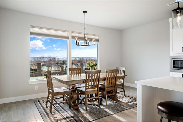 dining space with an inviting chandelier and light hardwood / wood-style flooring