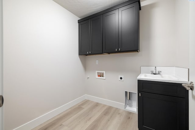 clothes washing area featuring light hardwood / wood-style flooring, washer hookup, hookup for an electric dryer, sink, and cabinets