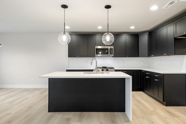 kitchen featuring a center island with sink, pendant lighting, and backsplash