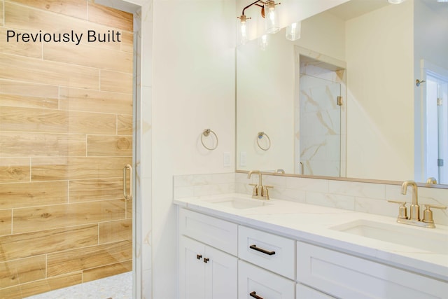 bathroom featuring double vanity, a stall shower, and a sink