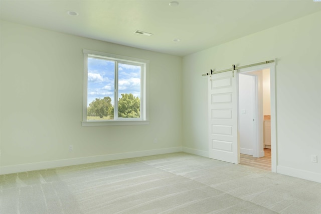 4003 Rd 96, Pasco, WA 99301 - unfurnished bedroom with a barn door, light carpet, and baseboards