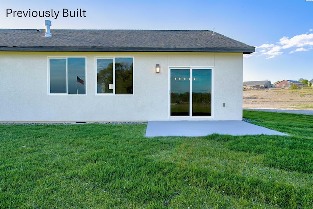 back of property with a yard, a patio, roof with shingles, and stucco siding