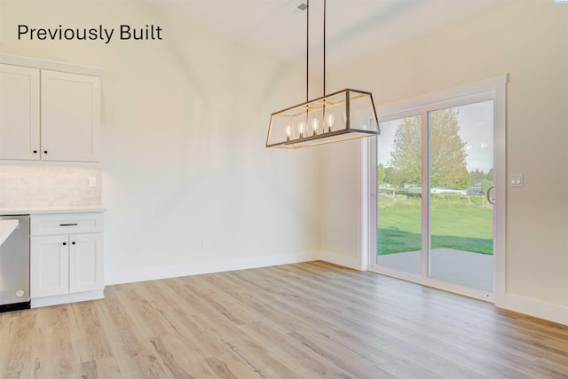 unfurnished dining area featuring a chandelier, baseboards, and light wood-style floors