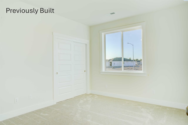 carpeted spare room with visible vents and baseboards