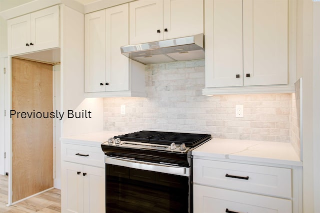 kitchen featuring under cabinet range hood, white cabinetry, light wood-style floors, decorative backsplash, and gas range