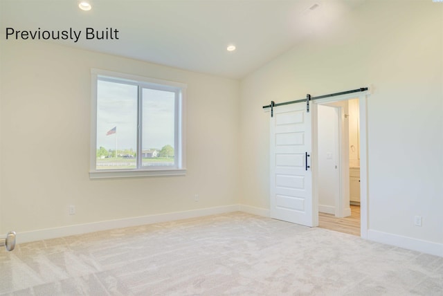 unfurnished room featuring a barn door, recessed lighting, baseboards, and light carpet