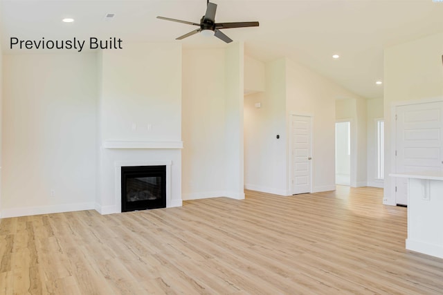 unfurnished living room with recessed lighting, light wood-style flooring, baseboards, and a glass covered fireplace