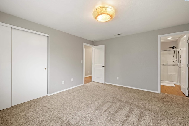 unfurnished bedroom with baseboards, visible vents, ensuite bathroom, carpet floors, and a closet