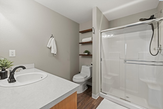 bathroom with vanity, a stall shower, wood finished floors, and toilet