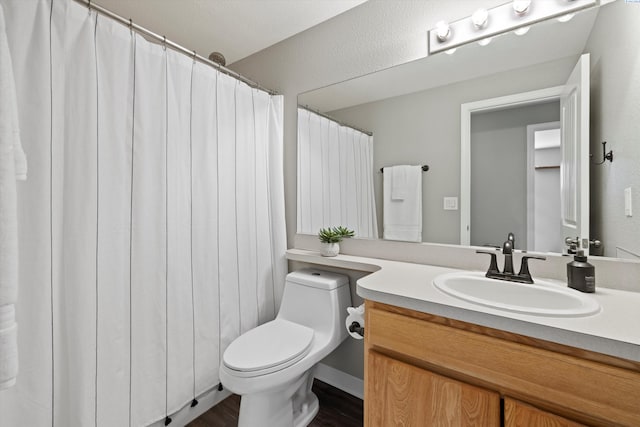 full bath with toilet, wood finished floors, and vanity