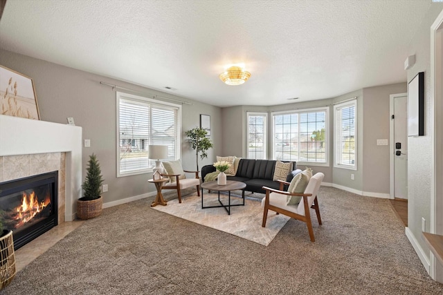 living area with carpet floors, a healthy amount of sunlight, a textured ceiling, and a tiled fireplace