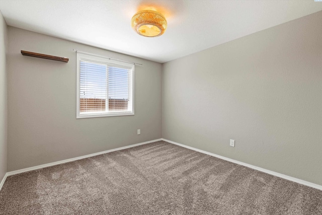 empty room featuring carpet and baseboards