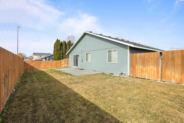 rear view of property with a patio, a lawn, and a fenced backyard