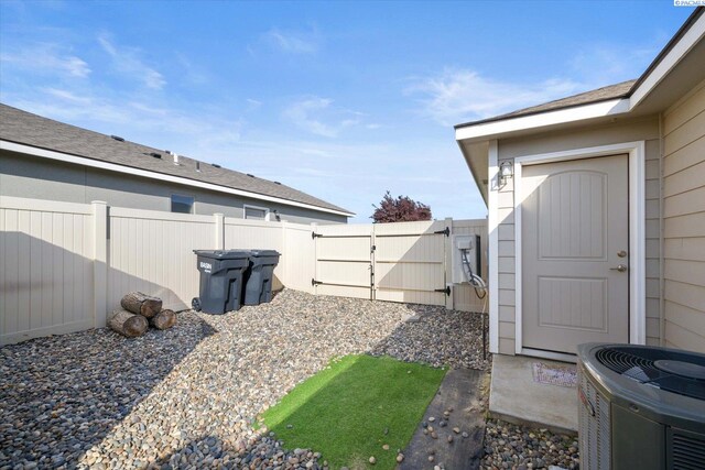 view of yard featuring central AC unit, fence, and a gate