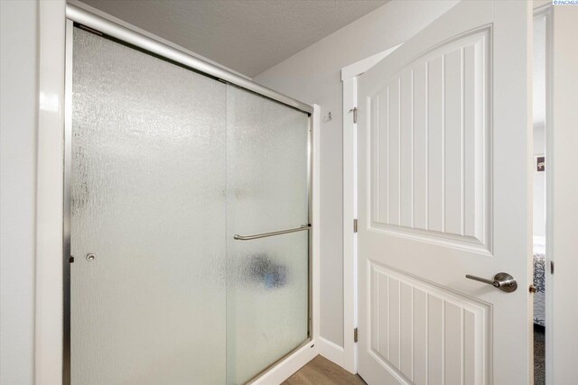 full bathroom featuring a shower stall and wood finished floors