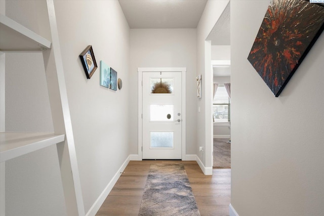 doorway with baseboards and wood finished floors