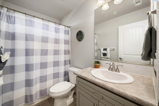 full bathroom featuring vanity, toilet, a shower with shower curtain, wood finished floors, and visible vents