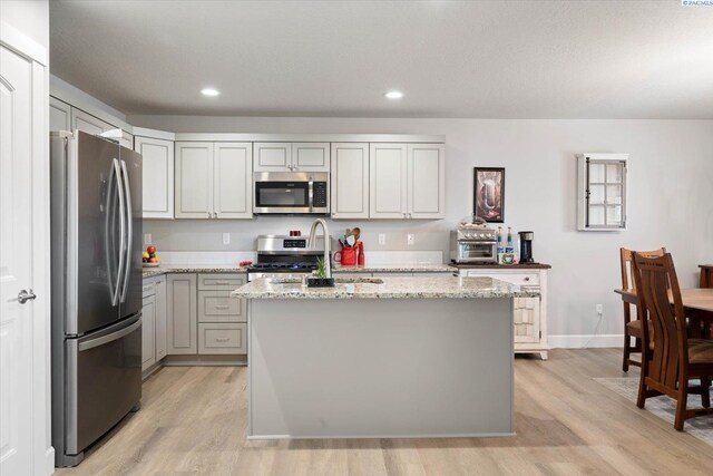 kitchen featuring light wood-style floors, appliances with stainless steel finishes, and light stone counters