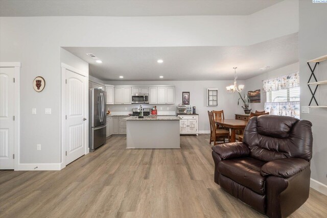 kitchen with appliances with stainless steel finishes, light wood-type flooring, a sink, open floor plan, and an inviting chandelier