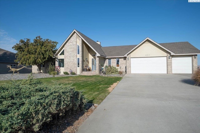 view of front facade with a garage, brick siding, driveway, and a front yard