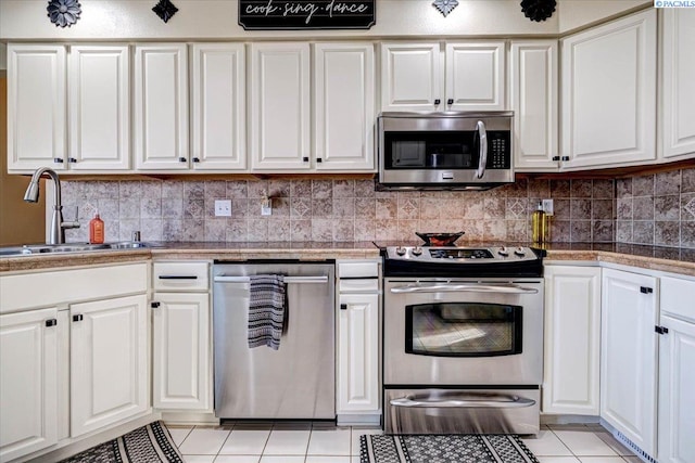 kitchen with light tile patterned floors, backsplash, appliances with stainless steel finishes, white cabinetry, and a sink