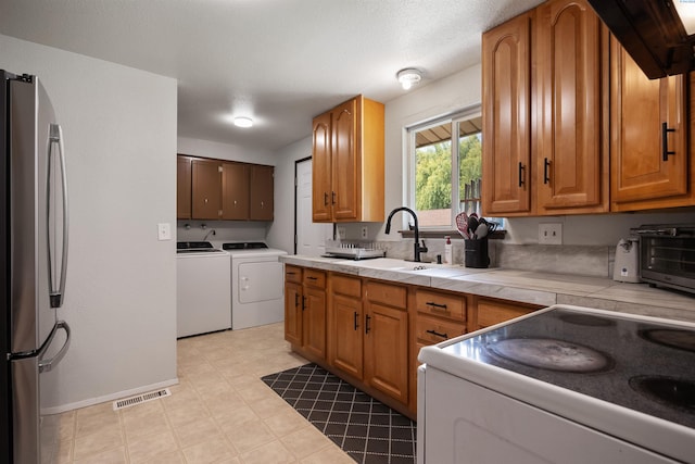 506 W 19th Ave, Kennewick, WA 99337 - kitchen featuring freestanding refrigerator, washer and clothes dryer, tile countertops, brown cabinets, and white electric stove