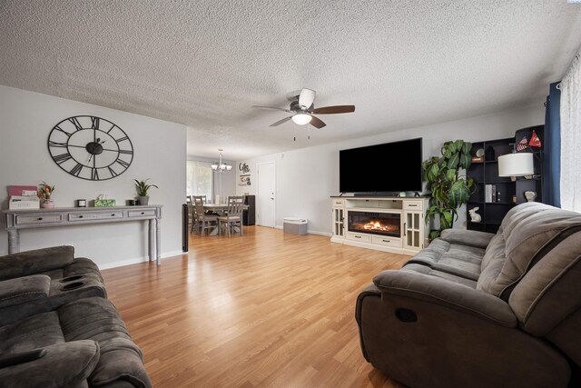 506 W 19th Ave, Kennewick, WA 99337 - living room with a ceiling fan, a textured ceiling, light wood finished floors, a chandelier, and a glass covered fireplace