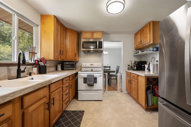 506 W 19th Ave, Kennewick, WA 99337 - kitchen with stainless steel appliances, light countertops, brown cabinetry, and light tile patterned flooring