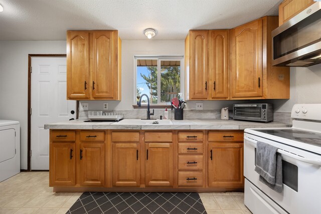 506 W 19th Ave, Kennewick, WA 99337 - kitchen with white range with electric stovetop, stainless steel microwave, washer / clothes dryer, a textured ceiling, and tile counters