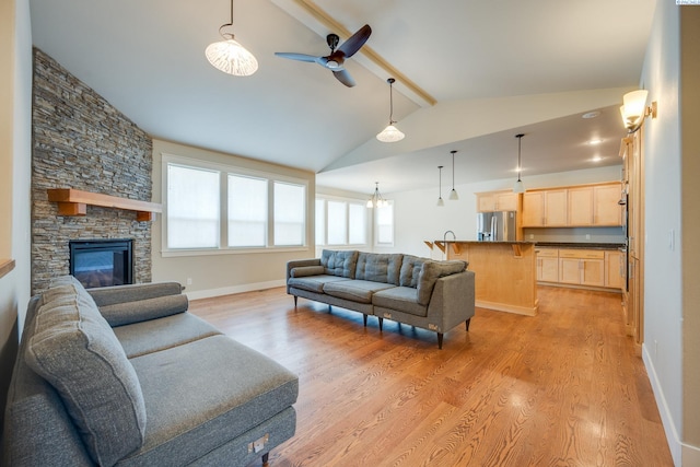 living room with a fireplace, ceiling fan with notable chandelier, light hardwood / wood-style flooring, and lofted ceiling with beams