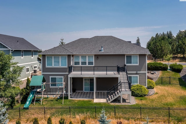 rear view of property with a playground and a lawn