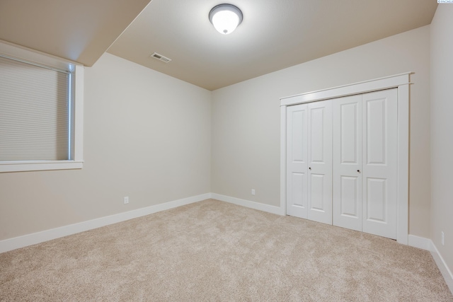 unfurnished bedroom featuring light carpet and a closet