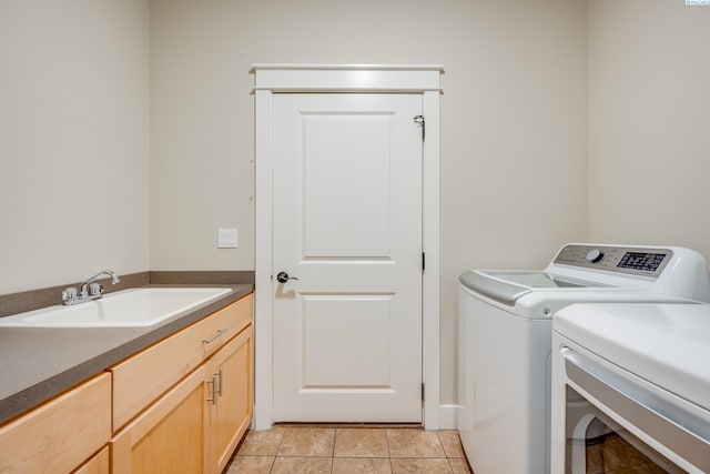 washroom featuring sink, light tile patterned floors, washer and clothes dryer, and cabinets