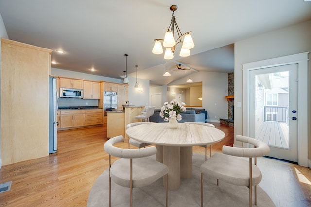 dining space featuring lofted ceiling, a notable chandelier, and light wood-type flooring