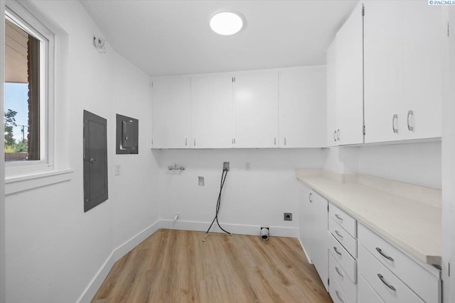 clothes washing area with light hardwood / wood-style floors, hookup for a washing machine, electric panel, and cabinets