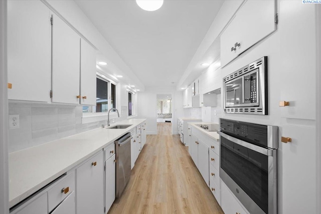 kitchen with tasteful backsplash, white cabinetry, appliances with stainless steel finishes, and sink