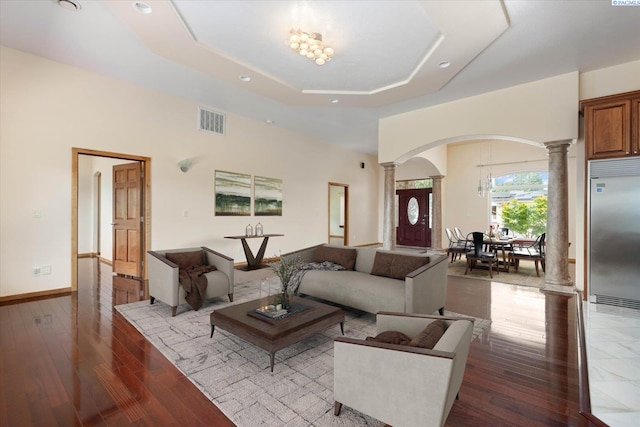 living room with decorative columns, light hardwood / wood-style flooring, and a tray ceiling