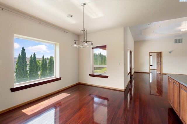 unfurnished dining area with a healthy amount of sunlight, dark wood-type flooring, and a chandelier