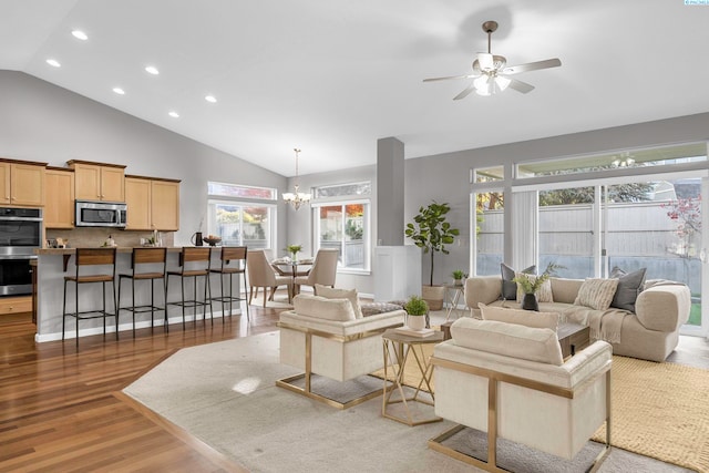 living room with high vaulted ceiling, dark hardwood / wood-style floors, and ceiling fan with notable chandelier