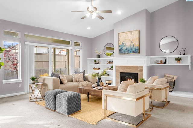 carpeted living room featuring a tiled fireplace, ceiling fan, and high vaulted ceiling