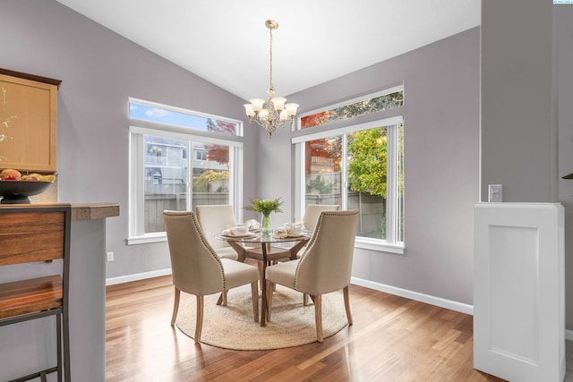 dining area with vaulted ceiling, a chandelier, and light hardwood / wood-style flooring